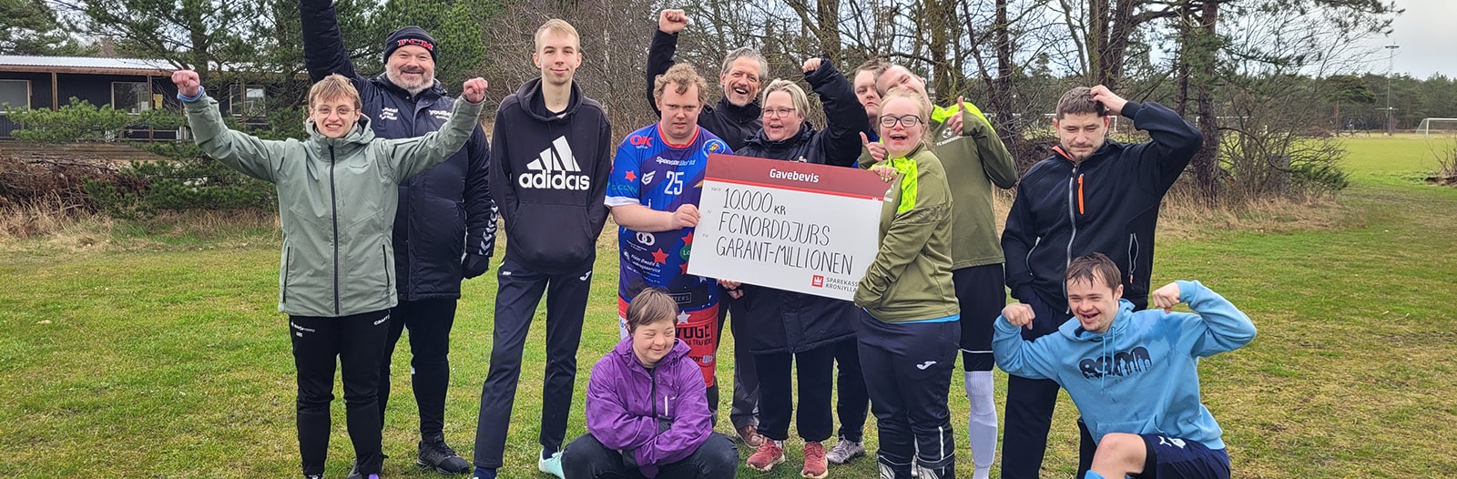 Afdelingsdirektør Anders Jelle (bagerst i midten) overrækker et gavebevis på 10.000 kr. til FC Norddjurs.