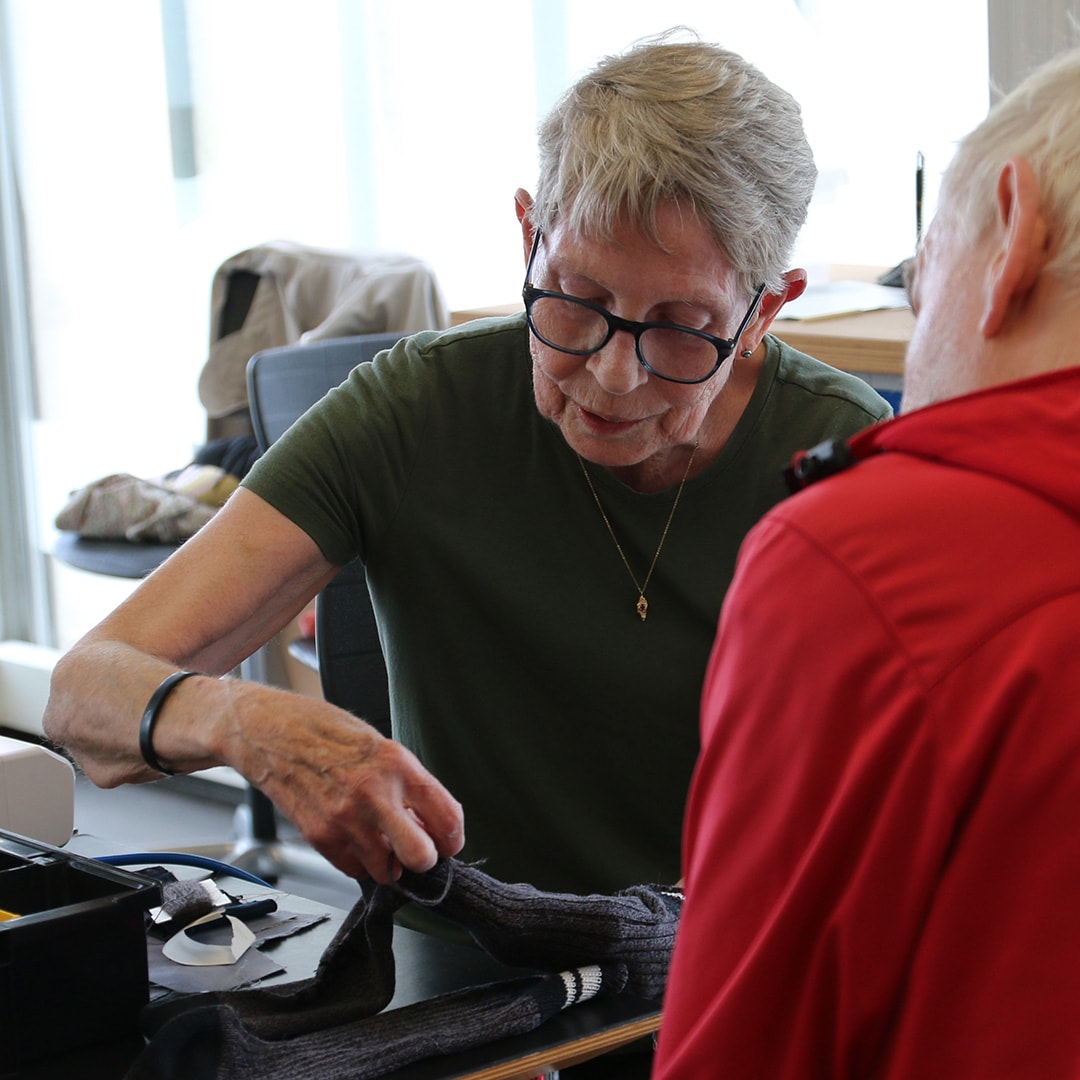 Ingelise Sørensen viser, hvordan man stopper et hul i et par sokker, på Repair Café Randers
