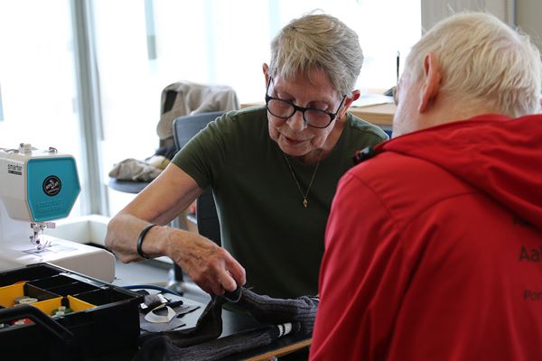 Ingelise Sørensen er frivillig i Repair Café Randers og hjælper her en gæst med at reparere et par strømper.
